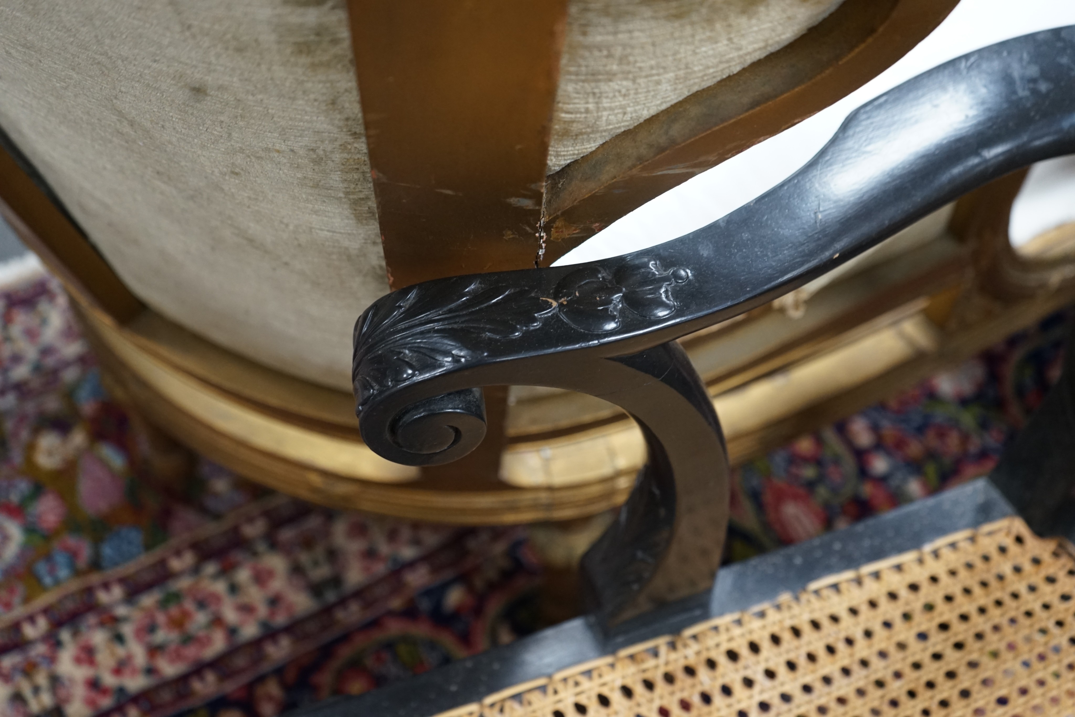 An 18th century style ebonised caned Irish elbow chair, width 70cm, depth 46cm, height 107cm (top rail requires restoration)